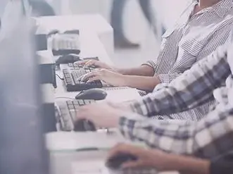 A group of people sitting at computers with keyboards.